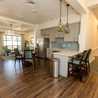 A modern open floor plan featuring a kitchen with bar seating and a dining area, highlighted by wood flooring and stylish chandeliers.
