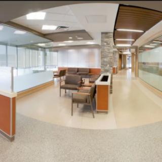 A modern hospital waiting room with comfortable seating and glass partitions.