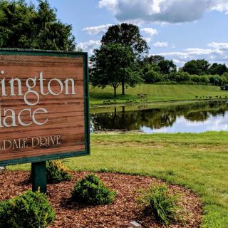 Entrance sign for Lexington Place by a scenic pond.
