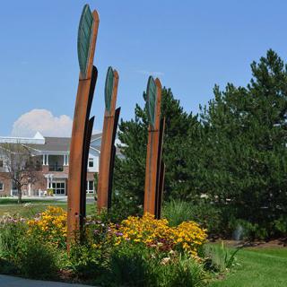 Outdoor sculpture surrounded by vibrant flowers and greenery.