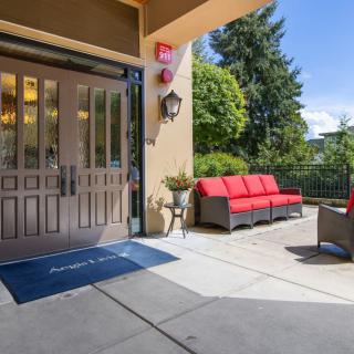 A sunny patio area with red-cushioned seating and a garden view, adjacent to an entrance.