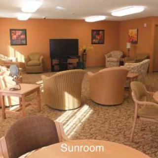 A cozy sunroom with comfortable seating and a television.