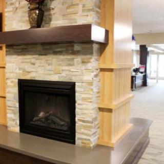 A cozy fireplace with a stone wall surround and wooden mantel in a modern interior setting.
