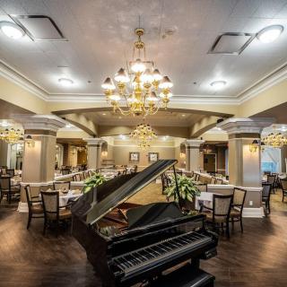 A luxurious restaurant interior featuring a grand piano and elegant chandeliers.