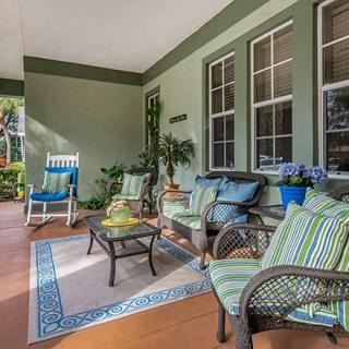 A cozy porch with comfortable chairs, cushions, and vibrant plants.
