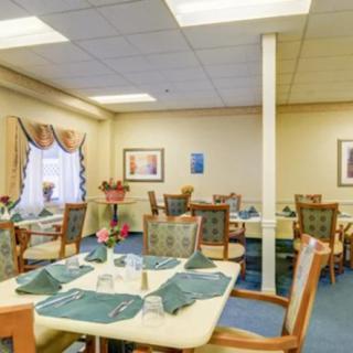 A cozy dining room setup with neatly arranged tables and chairs, adorned with decorative napkins and artwork on the walls.