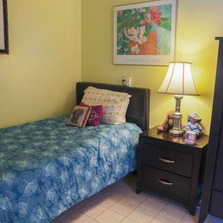 A cozy bedroom with a single bed, nightstand, and warm lighting.