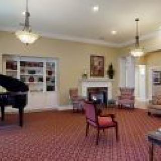 A spacious living room with a grand piano, elegant furnishings, and a cozy fireplace.