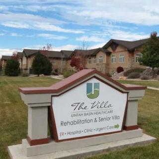 Sign for a rehabilitation and senior living facility in front of a large building.