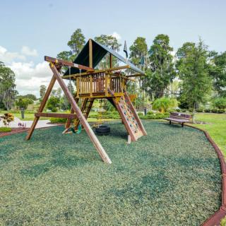 A wooden playground set in a lush, green outdoor area.