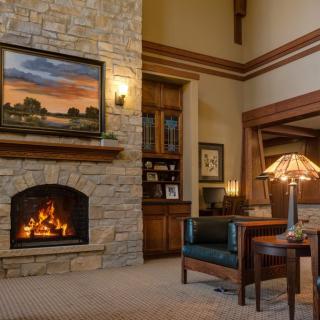 A cozy living room with a stone fireplace, an armchair, and warm lighting.