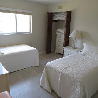 A simple bedroom with two single beds, a window, and minimal furnishings.