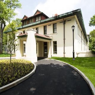 A beautiful residential house surrounded by a lush garden with a winding pathway.