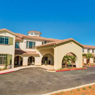 A sunny view of a two-story residential building with palm trees and a welcoming entrance.