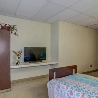 A simple bedroom with a TV, bed, and wardrobe.