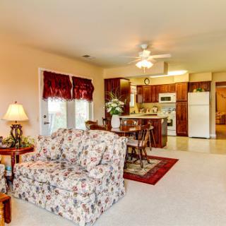 A cozy open concept living room and kitchen featuring floral furniture and warm lighting.