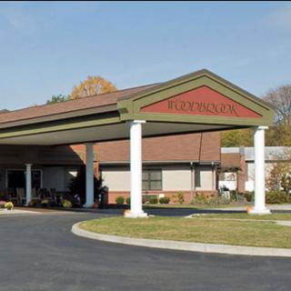 A building with a covered entrance and columns leading to a driveway.