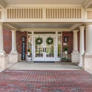 The entrance of a building decorated with wreaths and a welcome sign.