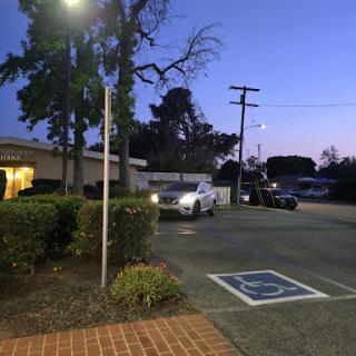 A quiet parking lot during twilight with a street light illuminating the area.