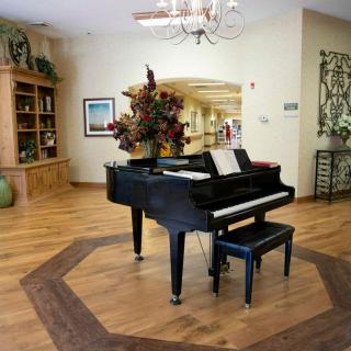 A grand piano is elegantly placed in a well-decorated living space featuring wood floors and a chandelier.
