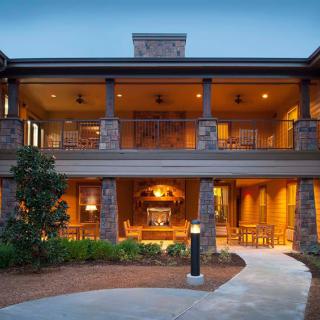A beautifully lit modern house with a spacious porch and well-maintained landscaping.