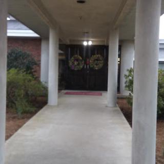 A view of the entrance pathway leading to a home, adorned with decorative wreaths on the double doors.