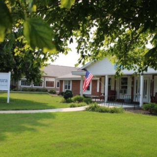 A cozy house with a well-maintained lawn and an American flag hanging from the porch.
