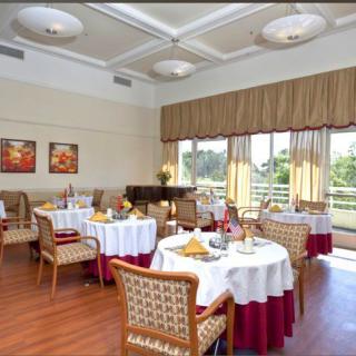 An elegant restaurant dining room with neatly arranged tables and chairs, featuring large windows allowing natural light to illuminate the space.