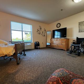 A spacious hospital room featuring a bed, wheelchair, and a view through the window.