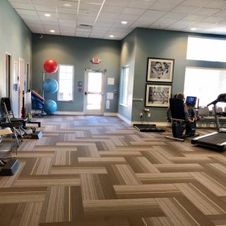 A well-lit gym featuring various exercise equipment including treadmills, dumbbells, and yoga balls.