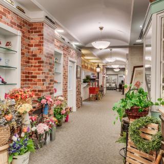 A charming indoor flower shop with brick walls and a variety of plants and flowers displayed along a hallway.