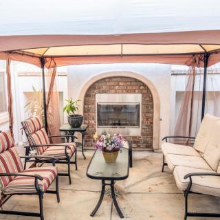 A cozy outdoor patio area with a fireplace, surrounded by comfortable seating and a canopy.