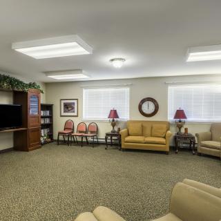 A cozy living room with sofas, chairs, a television, and a bookshelf.