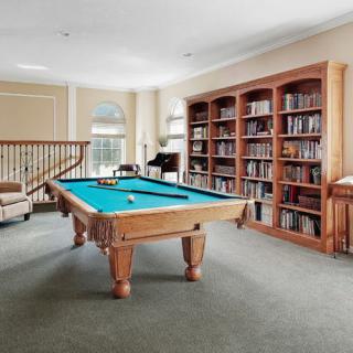 A bright room featuring a pool table and extensive bookshelves.