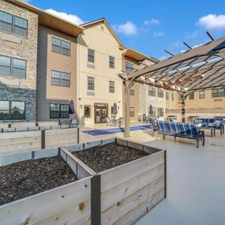 A modern building with an outdoor patio area featuring seating and planters under a clear blue sky.