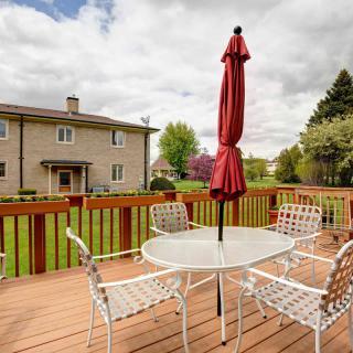 Outdoor patio with seating area and a red umbrella overlooking a spacious backyard.