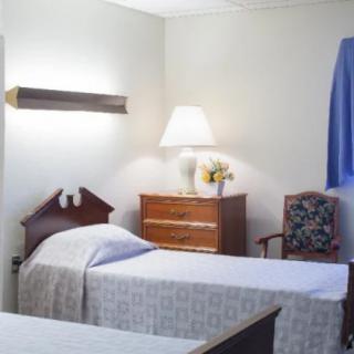 A cozy bedroom with twin beds, a dresser, and a lamp.