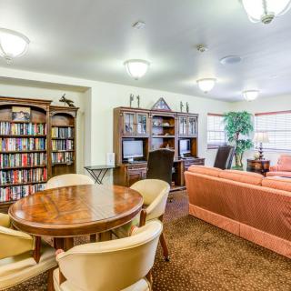 A cozy library room with bookshelves, a seating area, and a round table.
