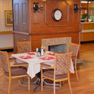 A cozy restaurant dining area featuring a table set for a meal, surrounded by wooden furniture and a charming wall clock.