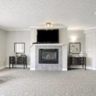 A spacious living room with a fireplace and wall-mounted TV, featuring elegant decor and furniture.