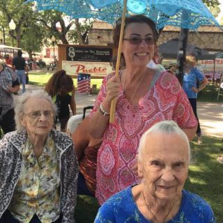 Three women enjoying a sunny day in the park, one holding an umbrella.