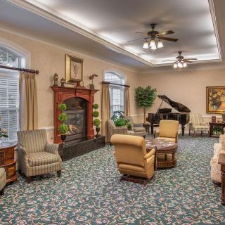 A cozy living room with comfortable seating, a fireplace, and a grand piano.