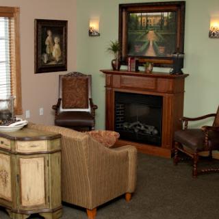 A cozy living room featuring a fireplace and comfortable seating, adorned with artwork.