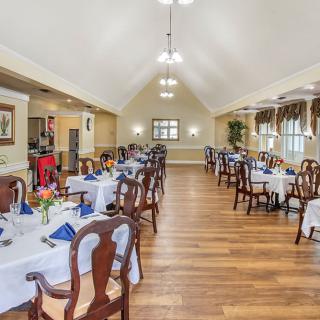 A spacious and elegant dining room with neatly arranged tables and chairs, featuring a warm interior design.