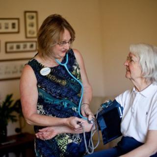 A nurse checks the blood pressure of an elderly patient in a care facility.
