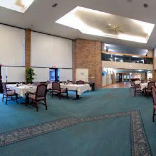A spacious dining area with tables and chairs, featuring modern design and carpeted flooring.