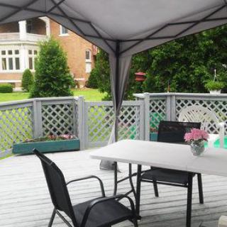 A cozy backyard patio setup featuring a canopy, table, and chairs with a view of the garden.