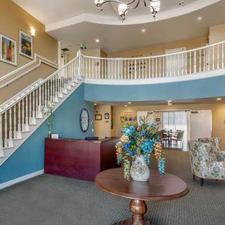 A welcoming lobby area featuring a grand staircase, a reception desk, and a table adorned with a floral arrangement.