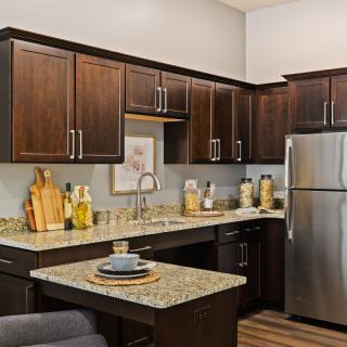 A modern kitchen with dark wood cabinets, granite countertops, and stainless steel appliances.
