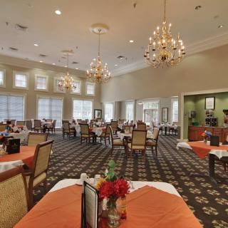 A spacious dining room with elegant chandeliers, neatly arranged tables and chairs.